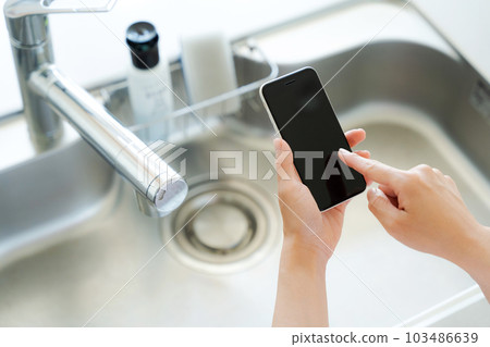 Hand photo with kitchen sink and smartphone Hand photo with kitchen sink and smartphone 103486639