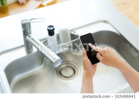 Hand photo with kitchen sink and smartphone Hand photo with kitchen sink and smartphone 103486641