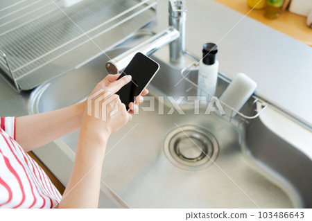 與廚房水槽和智能手機的手照片 103486643