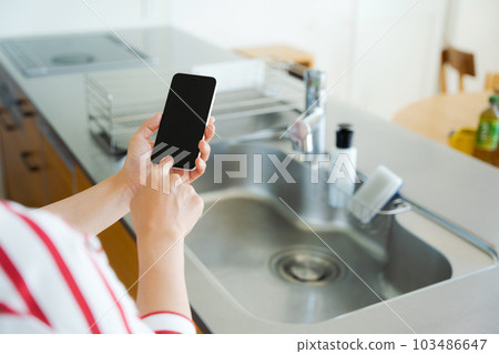 與廚房水槽和智能手機的手照片 103486647