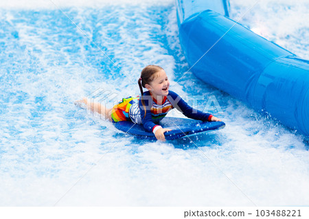 Little girl surfing in beach wave simulator 103488221