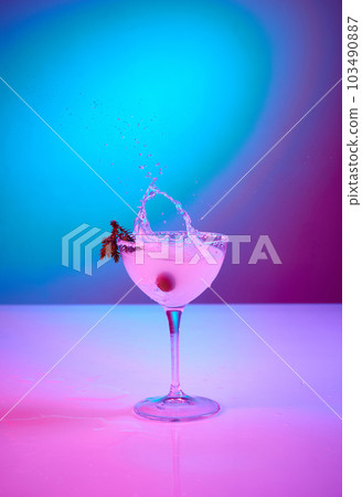 Tasty Margarita glass over pink gradient background in neon glow. Party club entertainment. Mixed light. Champagne splashes 103490887