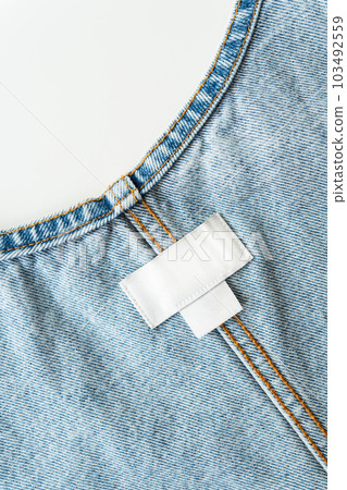 White label on denim clothes with size and brand, place for writing, mockup. Close-up. 103492559