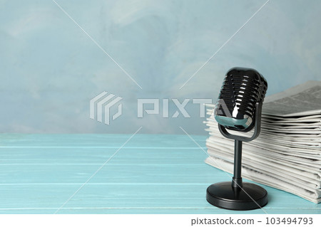 Newspapers and vintage microphone on light blue wooden table, space for text. Journalist's work Newspapers and vintage microphone on light blue wooden table, space for text. Journalist's work 103494793