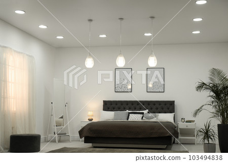 Stylish room interior with large comfortable bed Stylish room interior with large comfortable bed 103494838