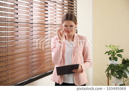 Professional psychotherapist with glasses and clipboard in office 103495069