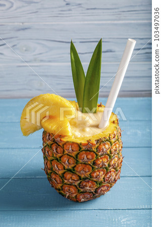 Vertical photo of exotic pineapple cocktail Pina colada on a blue wooden background Vertical photo of exotic pineapple cocktail Pina colada on a blue wooden background 103497036