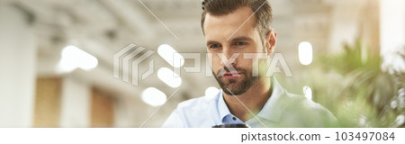 Enjoying morning coffee at work and checking e-mail 103497084