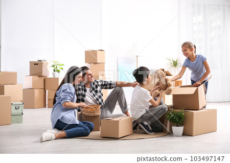 Happy family unpacking moving boxes at their new home 103497147