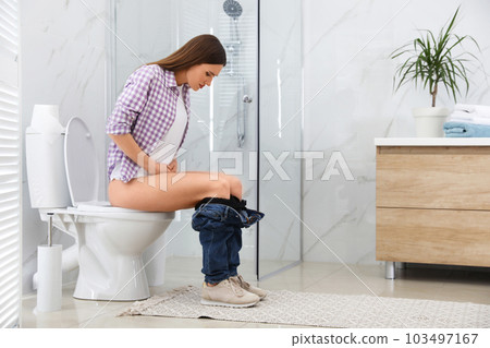 Woman suffering from hemorrhoid on toilet bowl in rest room Woman suffering from hemorrhoid on toilet bowl in rest room 103497167