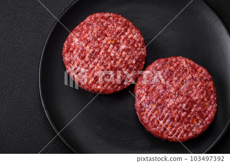 Fresh raw ground beef burger patty with salt and spices 103497392