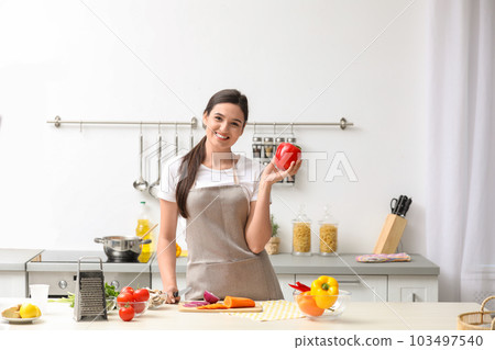 Young woman with bell pepper at table in kitchen. Cooking soup Young woman with bell pepper at table in kitchen. Cooking soup 103497540