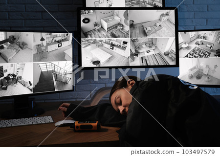 Female security guard sleeping near monitors at workplace Female security guard sleeping near monitors at workplace 103497579