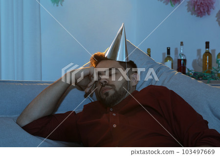 Young man with cap sleeping on sofa in room after party 103497669
