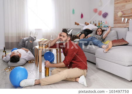 Drunk friends sleeping in messy room after party 103497750