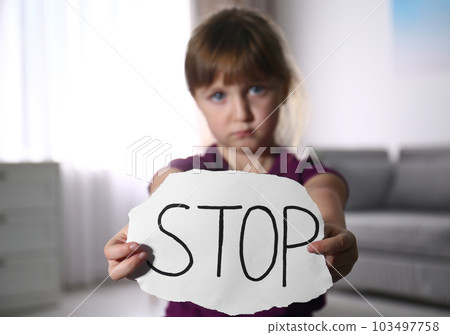Abused little girl with sign STOP indoors, focus on hands. Domestic violence concept 103497758