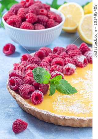 Lemon tart, garnished with fresh raspberry, icing sugar, mint, vertical Lemon tart, garnished with fresh raspberry, icing sugar, mint, vertical 103498408