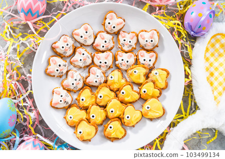 Easter chocolate-covered pretzel bunnies and ducklings on a white serving plate for the Easter table. 103499134