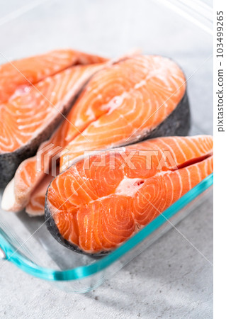Marinating salmon steaks in a glass dish for grilling. 103499265