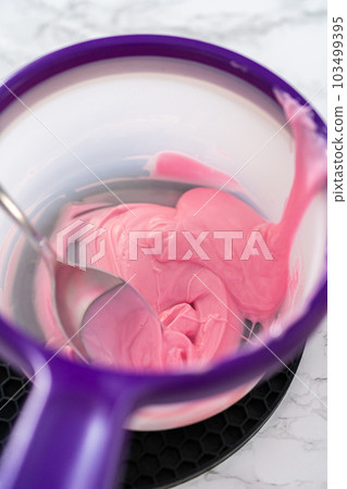 Preparing pink chocolate bows to decorate panda-shaped shortbread cookies. 103499395