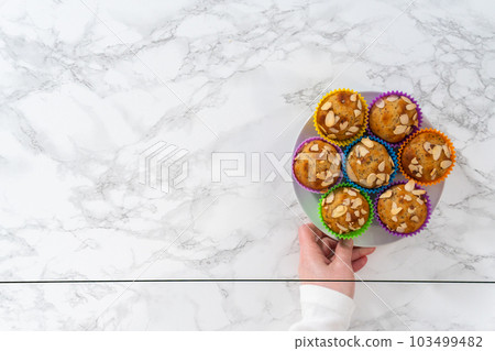 Flat lay. Freshly baked lemon poppy seed muffins garnished with almond slivers on the kitchen counter. 103499482