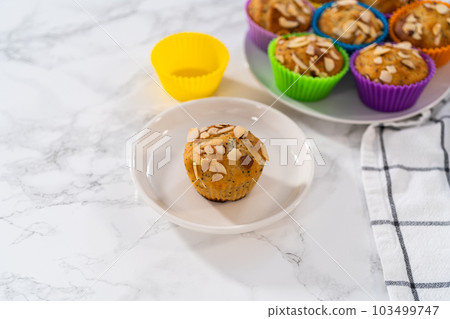 Freshly baked lemon poppy seed muffins garnished with almond slivers on the kitchen counter. 103499747