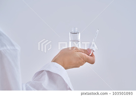 Female hands hold a cosmetic serum with a dropper. Female hands hold a cosmetic serum with a dropper. 103501093