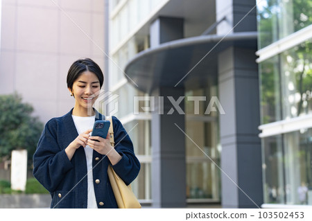 A woman using a smartphone in the city with a relaxed expression 103502453