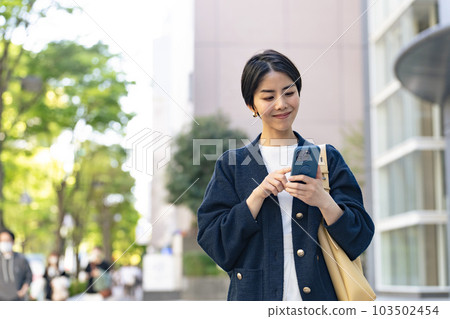 A woman using a smartphone in the city with a relaxed expression 103502454