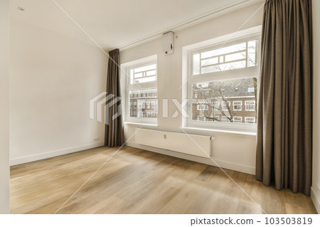 an empty room with wood flooring and two large windows in the photo is taken from inside, looking out to outside an empty room with wood flooring and two large windows in the photo is taken from inside, looking out to outside 103503819