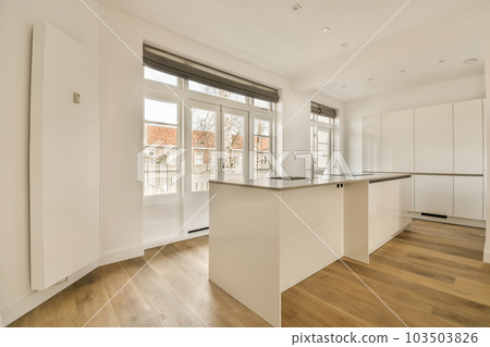 an empty kitchen with white cabinets and hardwood flooring in the middle section of this modern, open - plan apartment an empty kitchen with white cabinets and hardwood flooring in the middle section of this modern, open - plan apartment 103503826