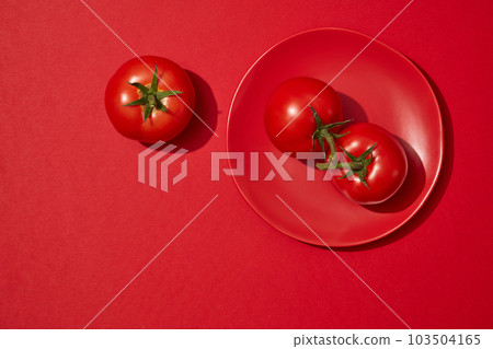 Over a red background, a dish with tomatoes are displayed. Blank space for beauty original product presentation of Tomato (Solanum lycopersicum) extract 103504165