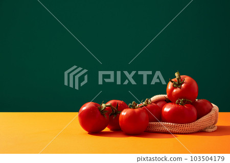 Front view of several red tomatoes over dark blue background. Tomato (Solanum lycopersicum) contains lots of vitamin A, a nutrient that helps keep hair healthy and shiny 103504179