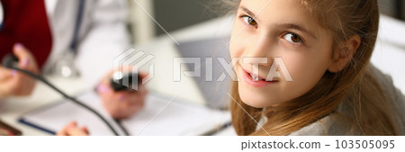 Doctor measures pressure of girl child in clinic 103505095