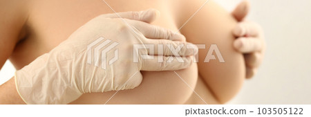 Woman with naked beautiful breasts closes nipples with gloved hands 103505122