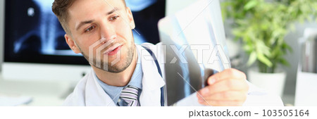Male doctor examines x-ray of leg and arm in clinic 103505164