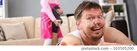 Little smiling girl holds father the leg, is lying on floor 103505200