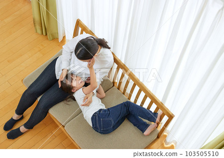 Mother relaxing with her child on the sofa Mother relaxing with her child on the sofa 103505510