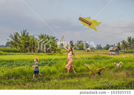 Mom and son launch a kite in a rice field in Ubud, Bali Island, Indonesia 103505555