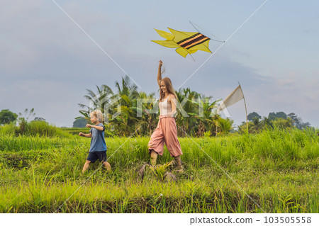 Mom and son launch a kite in a rice field in Ubud, Bali Island, Indonesia 103505558