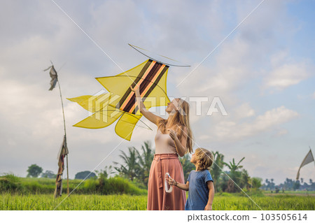 Mom and son launch a kite in a rice field in Ubud, Bali Island, Indonesia 103505614