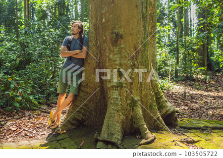 A man near a huge tree. The roots of an old tree, bali. Travel destination of Bali island, culture, art objects, of Indonesian people A man near a huge tree. The roots of an old tree, bali. Travel destination of Bali island, culture, art objects, of Indonesian people 103505722