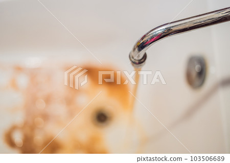 Dirty brown running water falling into a white sink from tap. Environmental pollution concept Dirty brown running water falling into a white sink from tap. Environmental pollution concept 103506689