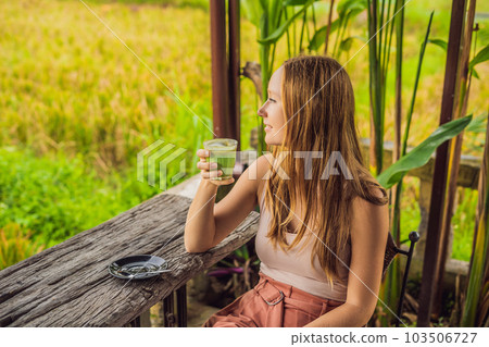 Young woman holding cup of matcha Latte, Green Tea, on old Wooden Background table Young woman holding cup of matcha Latte, Green Tea, on old Wooden Background table 103506727