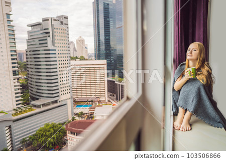 Woman wrapped in a blanket and looking at the big city Woman wrapped in a blanket and looking at the big city 103506866