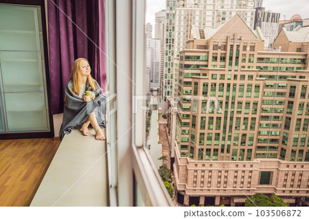 Woman wrapped in a blanket and looking at the big city 103506872