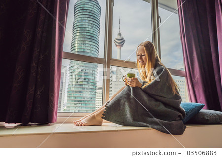 Woman wrapped in a blanket and looking at the big city Woman wrapped in a blanket and looking at the big city 103506883