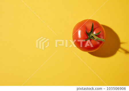 Top view of a red ripe fresh tomato on a yellow background. Blank space for text and design. The nutritional composition of tomatoes can protect the body from many dangerous diseases. 103506906