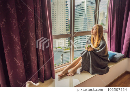 Woman wrapped in a blanket and looking at the big city 103507334
