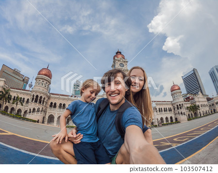 happy family makes selfie on the background on background of Merdeka square and Sultan Abdul Samad Building. Traveling with children concept happy family makes selfie on the background on background of Merdeka square and Sultan Abdul Samad Building. Traveling with children concept 103507412